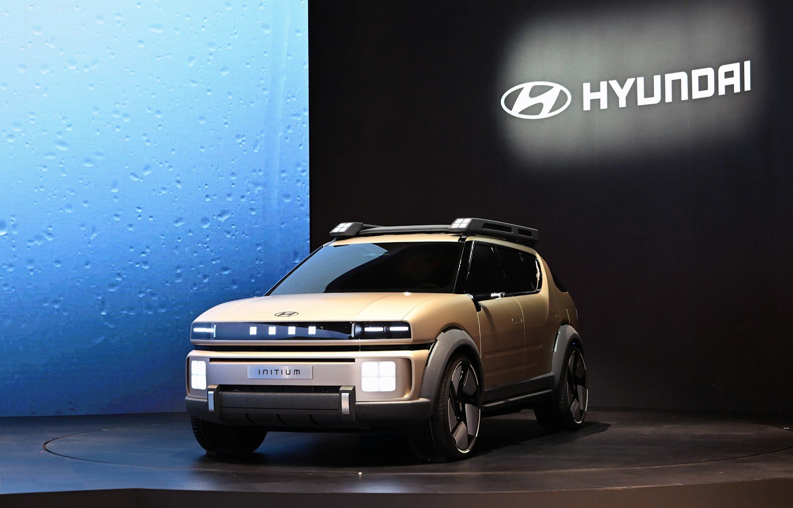 A small suv is on display in front of a sign